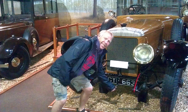 iw holding the cranking handle of an old car at the museum